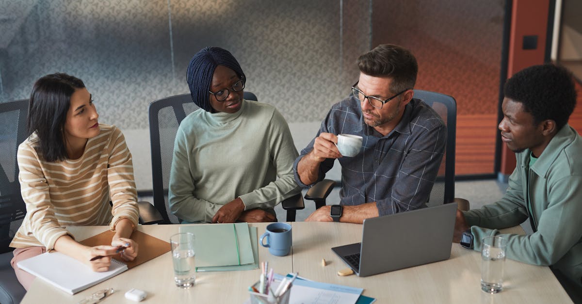 A diverse group of colleagues engaged in a discussion during a team meeting in a modern office.