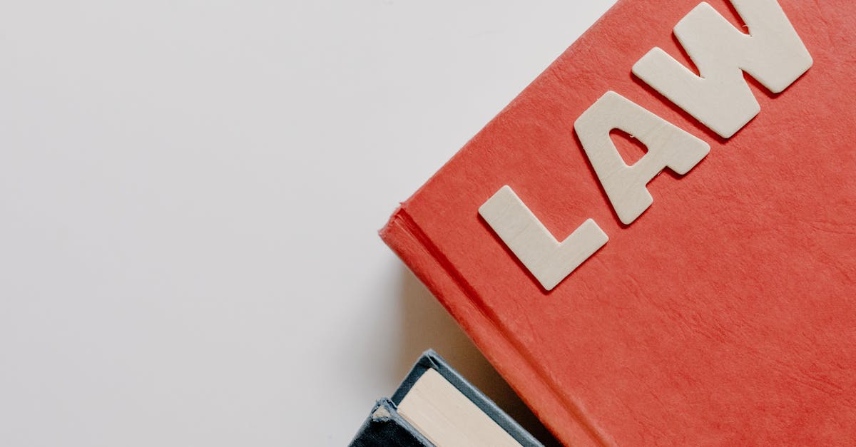 Red law textbook and dark book on white background, symbolizing education.